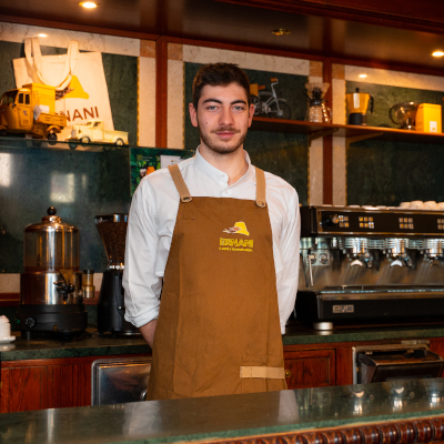 Davide, barista della Torrefazione Ernani a Milano, dietro al banco con la divisa: camicia bianca e grembiule marrone Ernani